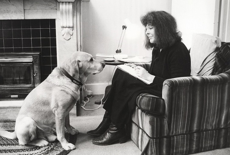 Diana Wynne Jones sitting on a chair with a dog in front of her